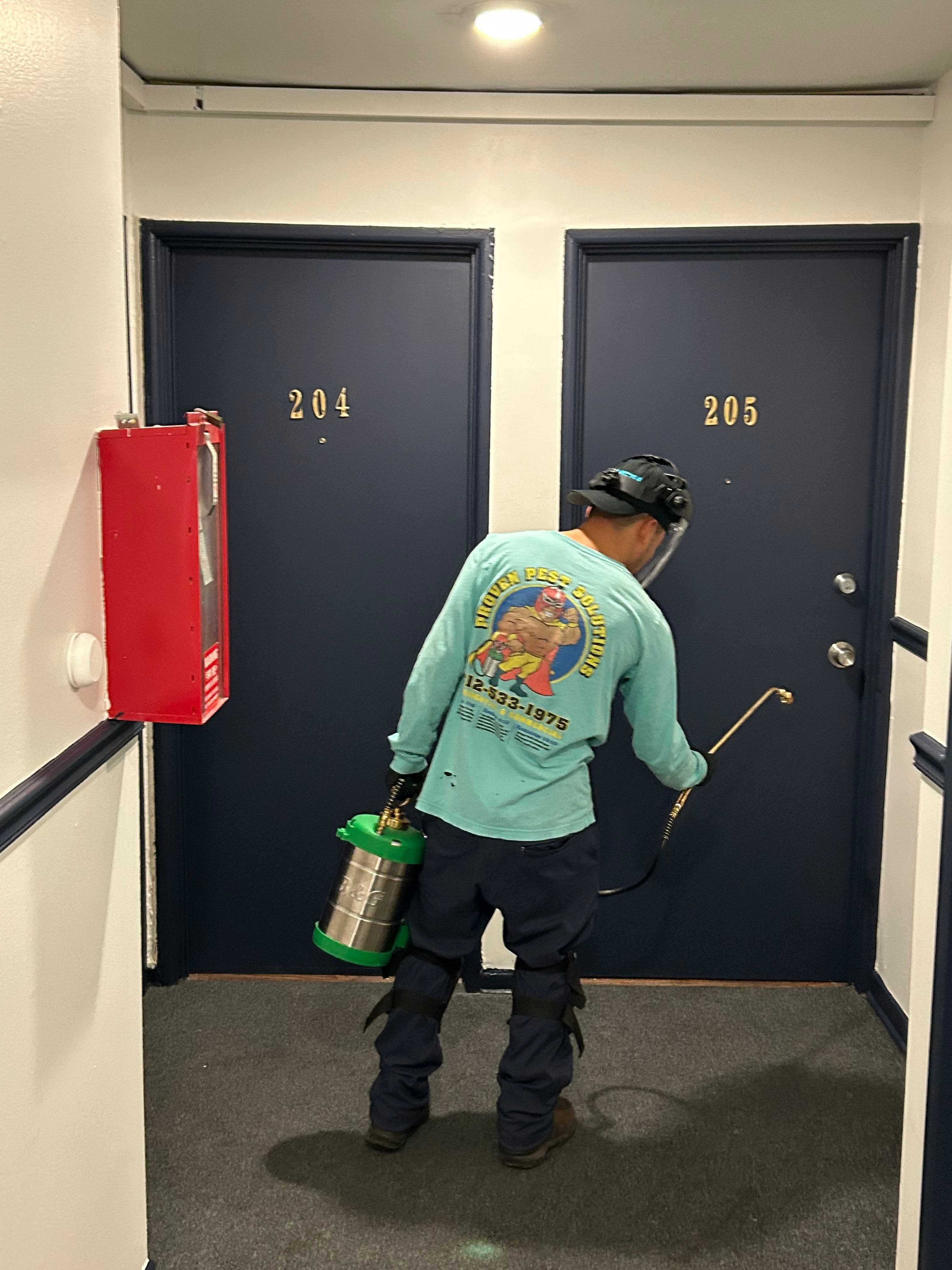 A pest technician treating an apartment hallway