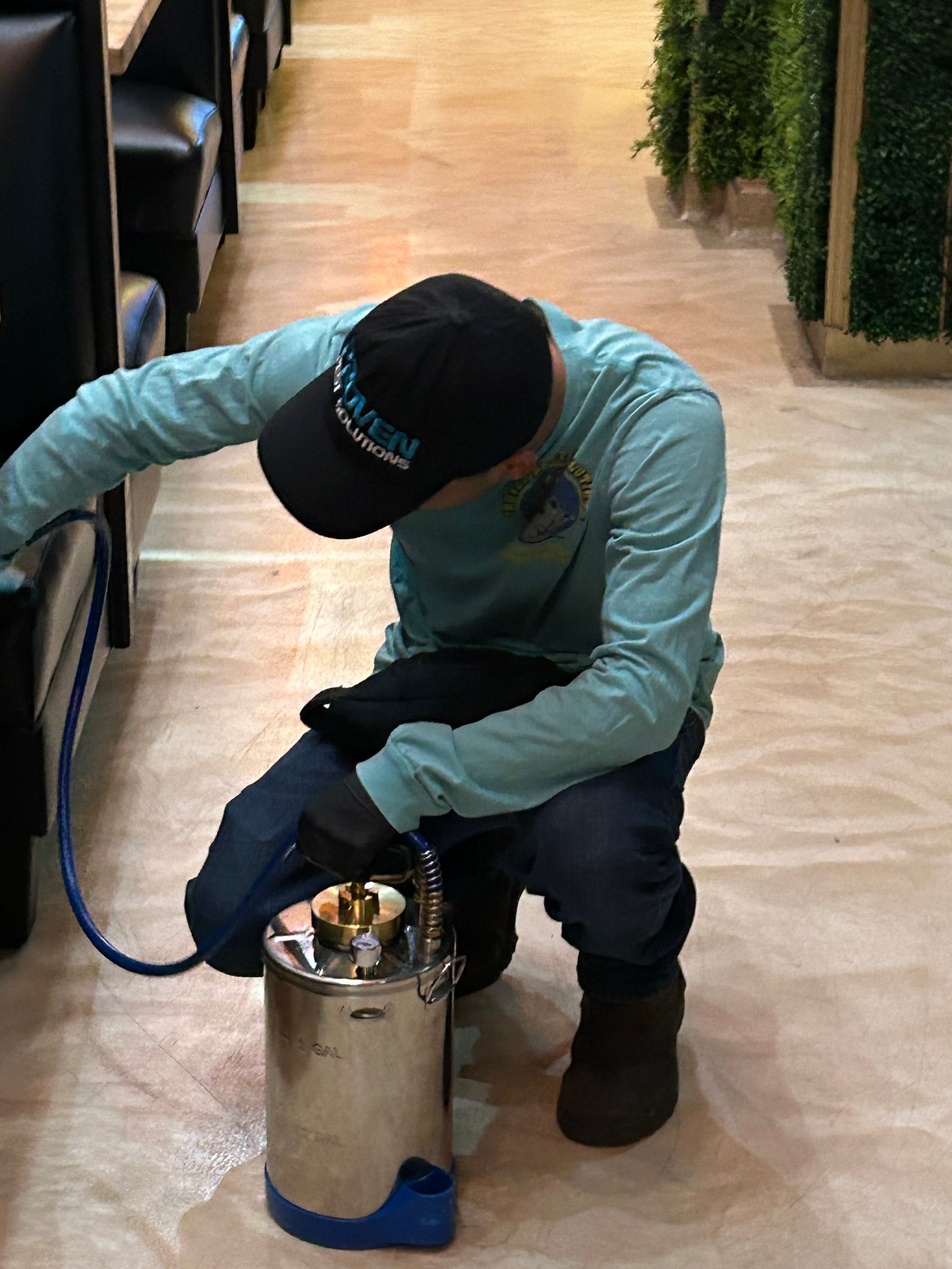 A pest technician inspecting beneath commercial seating