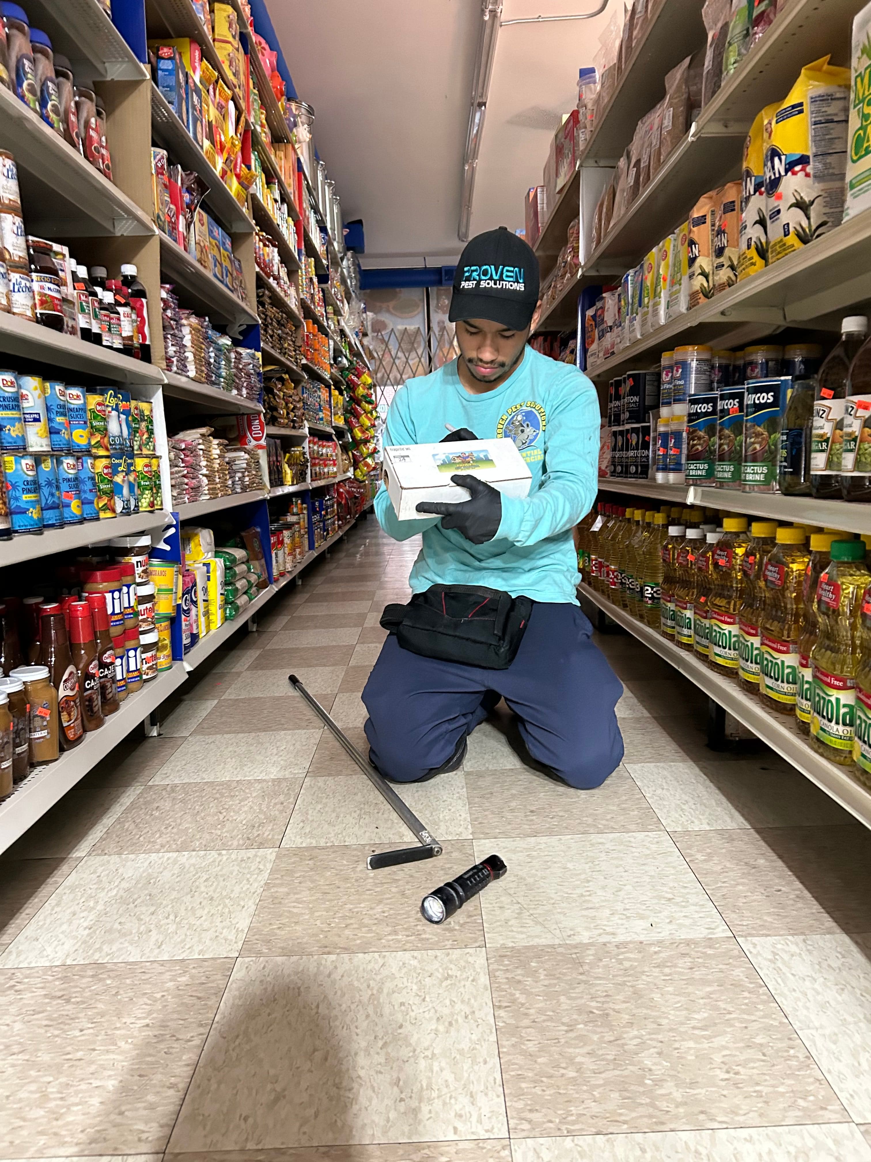 A pest technician inspecting a grocery store aisle